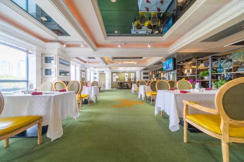 a dining room with white tables and yellow chairs at Ramada Yichang Hotel in Yichang