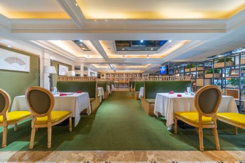 a restaurant with white tables and yellow chairs at Ramada Yichang Hotel in Yichang