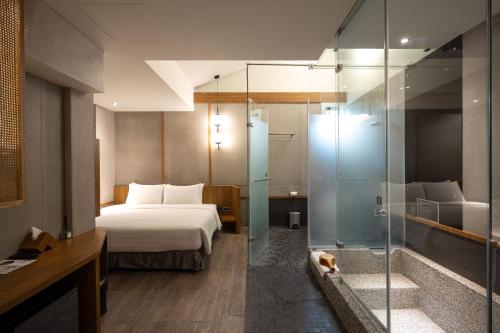 a hotel room with a bed and a glass shower at Yunoyado Onsen Hot Spring Hotel Deyang in Jiaoxi