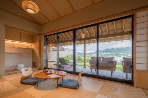 a living room with a table and chairs and large windows at Sesoko Sansui in Sesoko