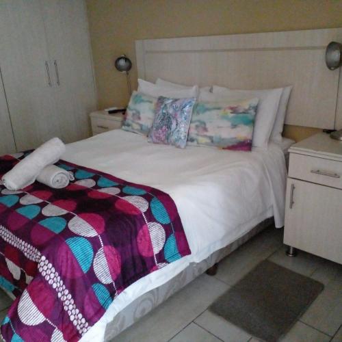 a bedroom with a white bed with a colorful blanket at LightStone Guesthouse in Centurion