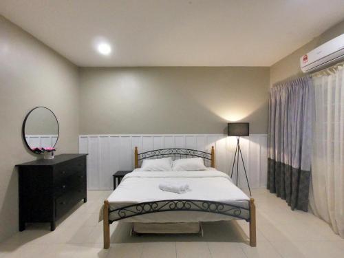 a bedroom with a bed and a dresser and a mirror at Lungo Guesthouse in Kuala Terengganu