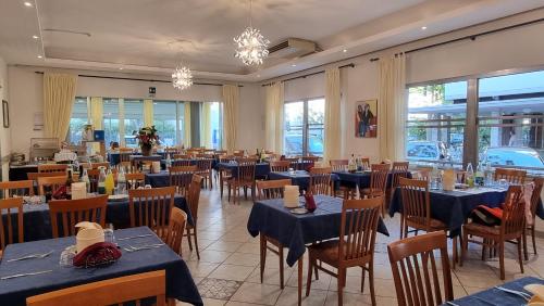 un restaurante con mesas y sillas azules y ventanas en Hotel Costanza en Cesenatico