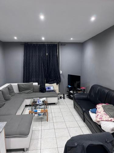 a living room with a couch and a tv at Grande maison avec plusieurs chambres à louer in Liège