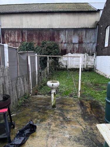 a dirty yard with a fence and a bird bath at Grande maison avec plusieurs chambres à louer in Liège