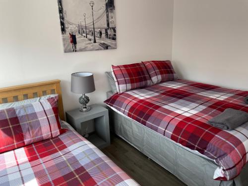 a bedroom with two beds and a lamp on a table at Rooms in Inverness in Inverness
