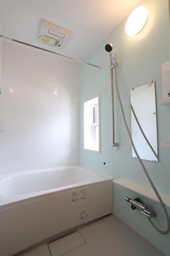 a bathroom with a bath tub and a mirror at Log Cottage 白馬KIITOS in Hakuba