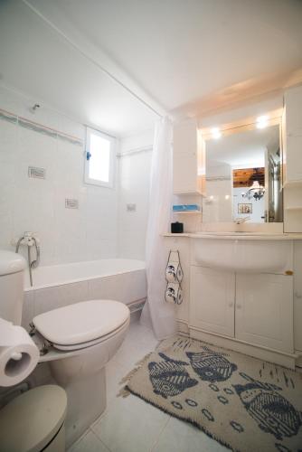 a white bathroom with a toilet and a tub and a sink at Sole Mykonos in Mikonos