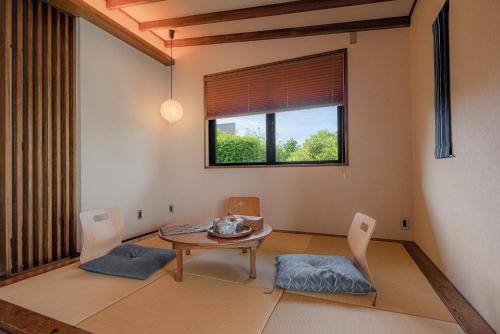 a dining room with a table and chairs and a window at Sesoko Sansui in Sesoko