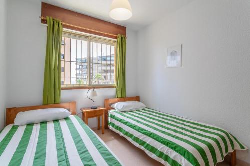 two beds in a room with green curtains and a window at Casa La Roqueta in Guardamar del Segura