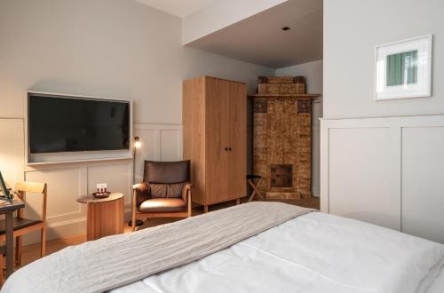 a bedroom with a bed and a chair and a tv at RUNO Hotel Porvoo in Porvoo