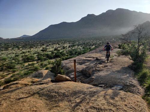 a person riding a bike on a rocky trail at Ai Aiba - The Rock Painting Lodge in Omaruru