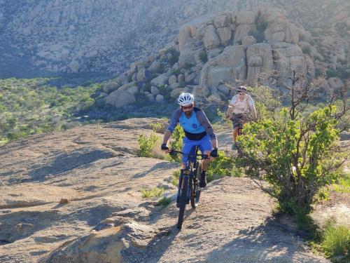 a man riding a bike on a rocky hill at Ai Aiba - The Rock Painting Lodge in Omaruru