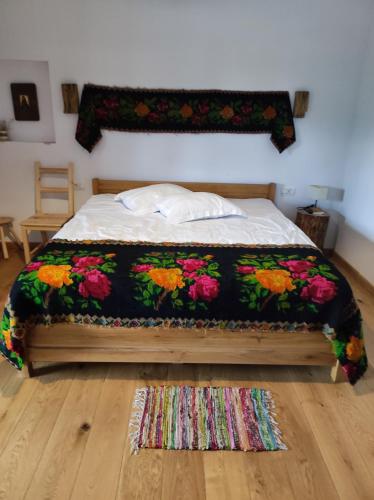 a bedroom with a bed with a floral blanket at Ograda Bunicilor in Baia de Fier