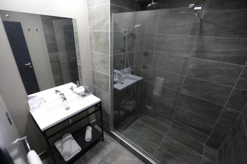 a bathroom with a shower and a sink and a mirror at Fiesta Royale Hotel in Accra