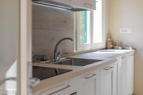 a white kitchen with a sink and a window at Appartamento La Triglia - HelloElba in Lacona
