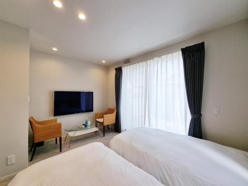 a hotel room with two beds and a flat screen tv at Lien 西新宿 in Tokyo