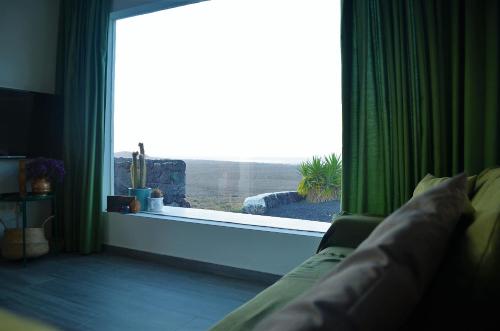 a living room with a large window with green curtains at EL REFUGIO in Famara
