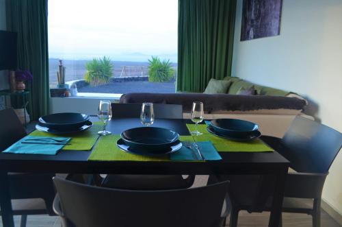 a dining table with two glasses and plates and a table with chairs at EL REFUGIO in Famara