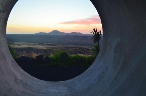 a view of a sunset through a round hole in a building at EL REFUGIO in Famara