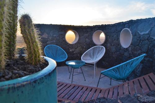 a stone wall with chairs and a table and a cactus at EL REFUGIO in Famara