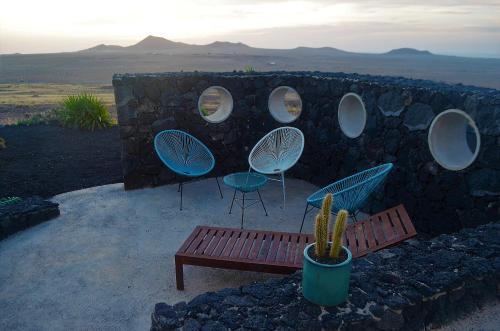 a stone wall with chairs and a bench and a cactus at EL REFUGIO in Famara