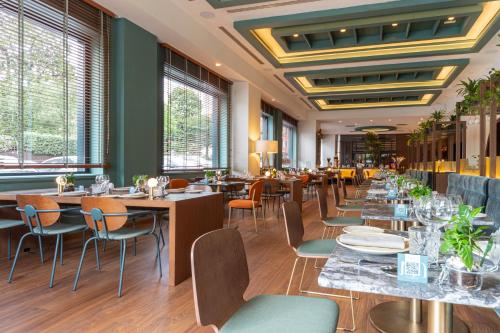 a restaurant with tables and chairs and windows at Meliá Milano in Milan