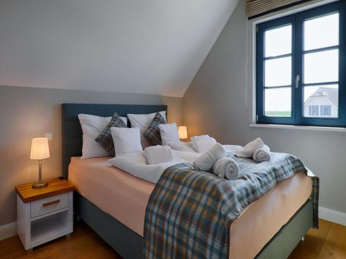 a bedroom with a bed with towels on it at Reetland am Meer - Premium Reetdachvilla mit 3 Schlafzimmern, Sauna und Kamin F26 in Dranske