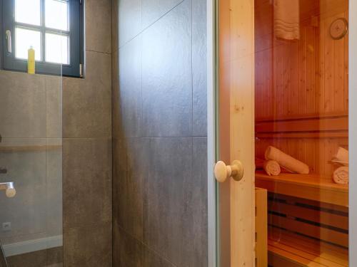 a bathroom with a shower and a glass door at Reetland am Meer - Premium Reetdachvilla mit 3 Schlafzimmern, Sauna und Kamin F26 in Dranske