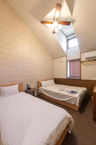 two beds in a room with a ceiling fan at ETAVIA Yufuin Kinrinko in Yufuin