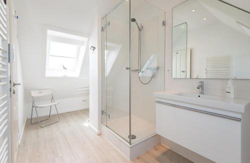 uma casa de banho com uma cabina de duche em vidro e um lavatório. em Käpt'n Gordon, App 15 em Wenningstedt