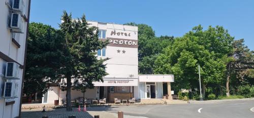 a building with a sign on the side of a street at Hotel Proton in Neptun