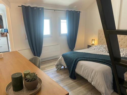 a bedroom with a bed with blue curtains and a table at Le bleu de Senlis in Senlis
