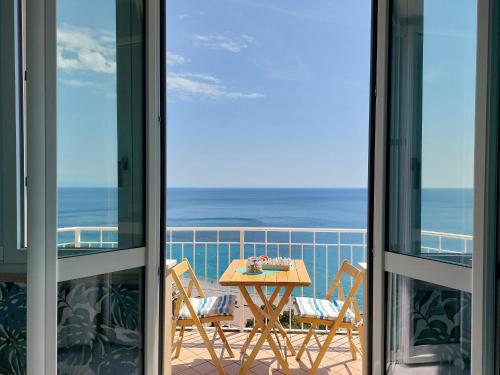 uma varanda com uma mesa e cadeiras e o oceano em Una finestra sul mare Home 1 em Bergeggi
