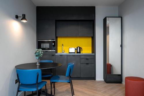 a kitchen with a table and blue chairs in a room at Staycity Aparthotels Dublin City Quay in Dublin