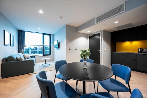 a living room with a table and blue chairs at Staycity Aparthotels Dublin City Quay in Dublin
