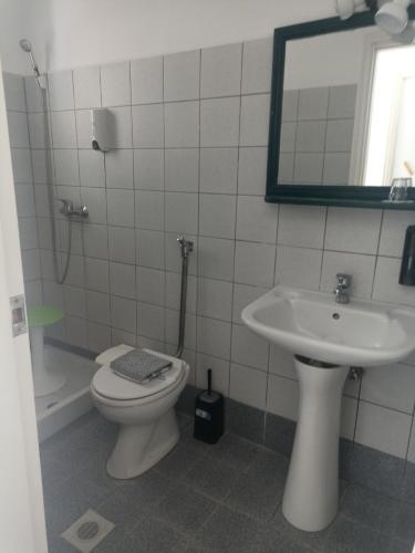 a bathroom with a sink and a toilet and a mirror at Pagali Hotel in Órmos Aiyialís
