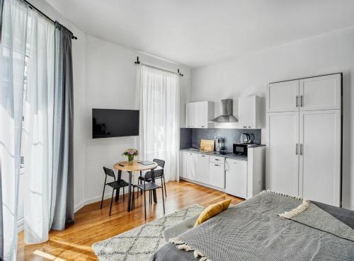 a white bedroom with a table and a kitchen at Berry Berry Studios by Flat White in Zagreb