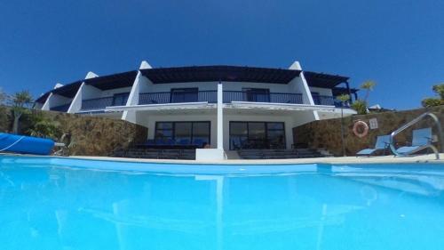 a large house with a swimming pool in front of it at Seafront Puerto Calero Villa in Puerto Calero
