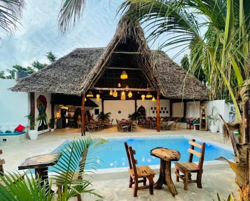 un complexe avec une piscine et un toit de chaume dans l'établissement Babalao Bungalows, à Nungwi