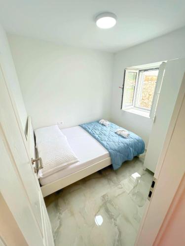 um pequeno quarto com uma cama e uma janela em Apartman Laura em Mlini