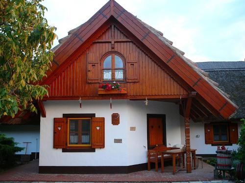 a house with a wooden roof with a table and a window at Zöld sziget Apartmanház in Gyenesdiás