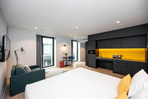 a living room with a bed and a yellow kitchen at Staycity Aparthotels Dublin City Quay in Dublin