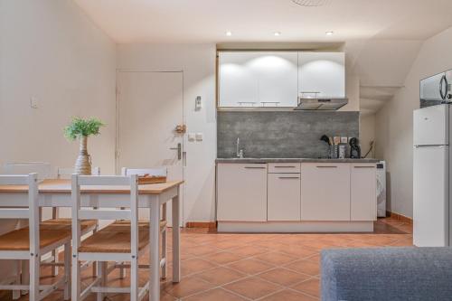 a kitchen with white cabinets and a table and chairs at Super studio climatisé in La Ciotat