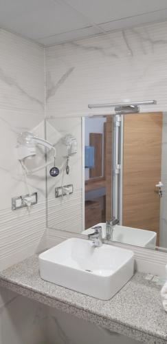 a bathroom with a white sink and a mirror at хотел ВИЗИЯ in Haskovo