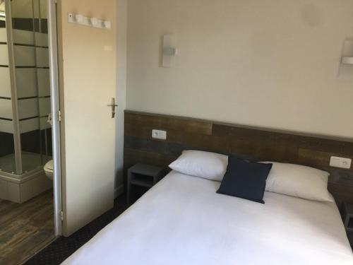 a bedroom with a white bed with a cross on the wall at Hotel TGV in Quimper