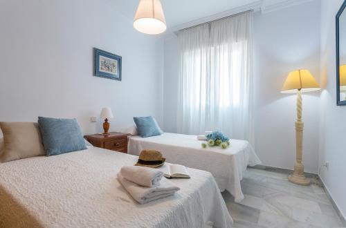 Habitación blanca con 2 camas y lámpara en Avenida Playa 3 Rooms 2 baños, en Cádiz