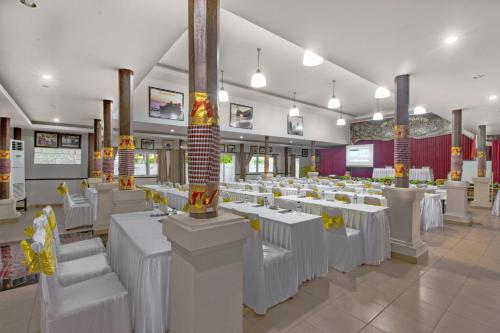 a dining room with white tables and white chairs at Dewi Sinta Hotel and Restaurant in Tanah Lot