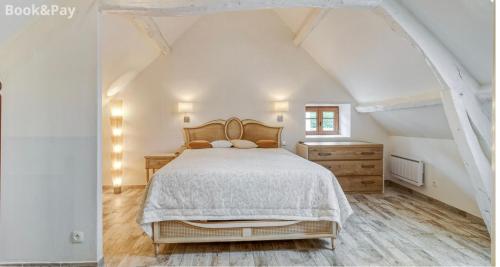 a white bedroom with a bed and a wooden floor at Harmonia maison de caractère proche PROVINS in Gouaix
