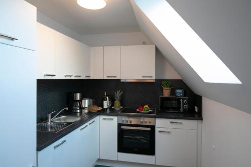a kitchen with white cabinets and a black counter top at Weberhof Ferienapartments in Rostrup am Westufer des Zwischenahner Meers in Bad Zwischenahn
